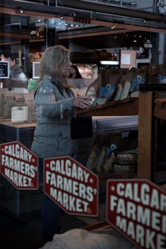 Woman shopping at Calgary Farmers Market with fresh produce and colorful stalls