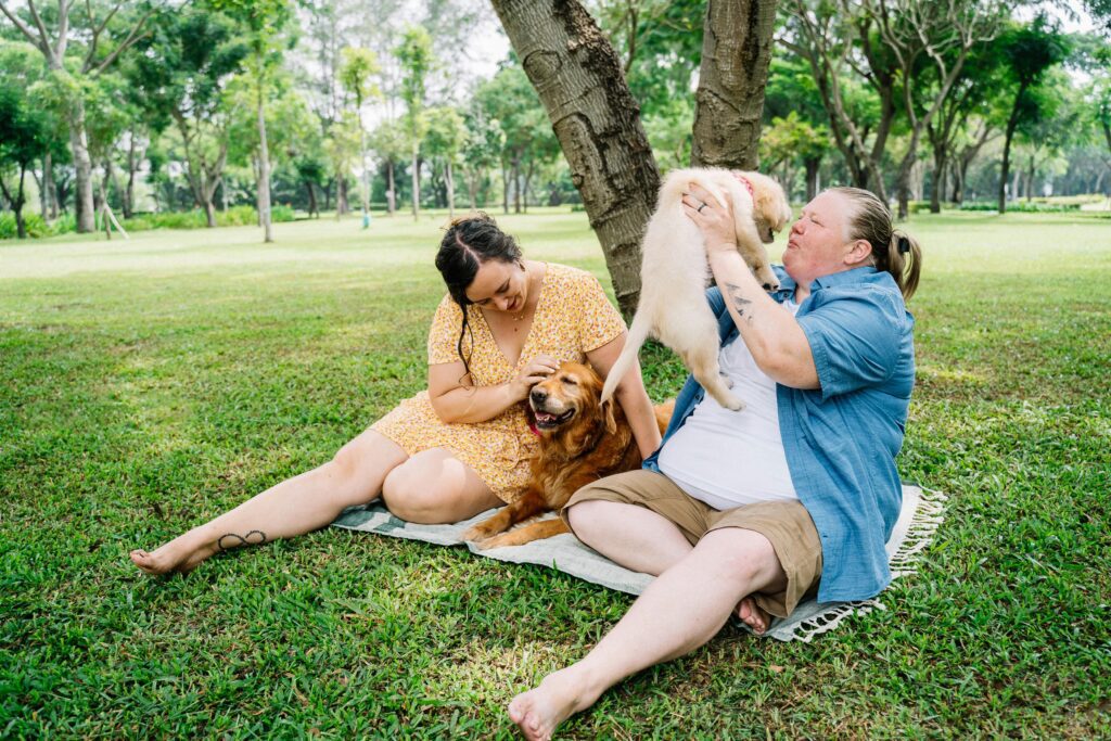 sitting on the grass with their dog in a park